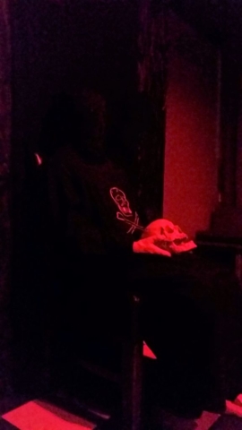 seated hooded ritualist holding a skull