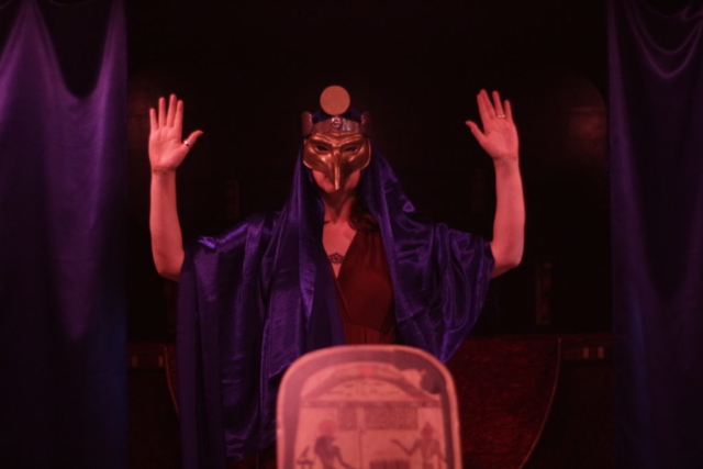 Ritualist dressed as Horus behind altar
