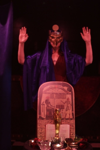 Ritualist dressed as Horus behind altar